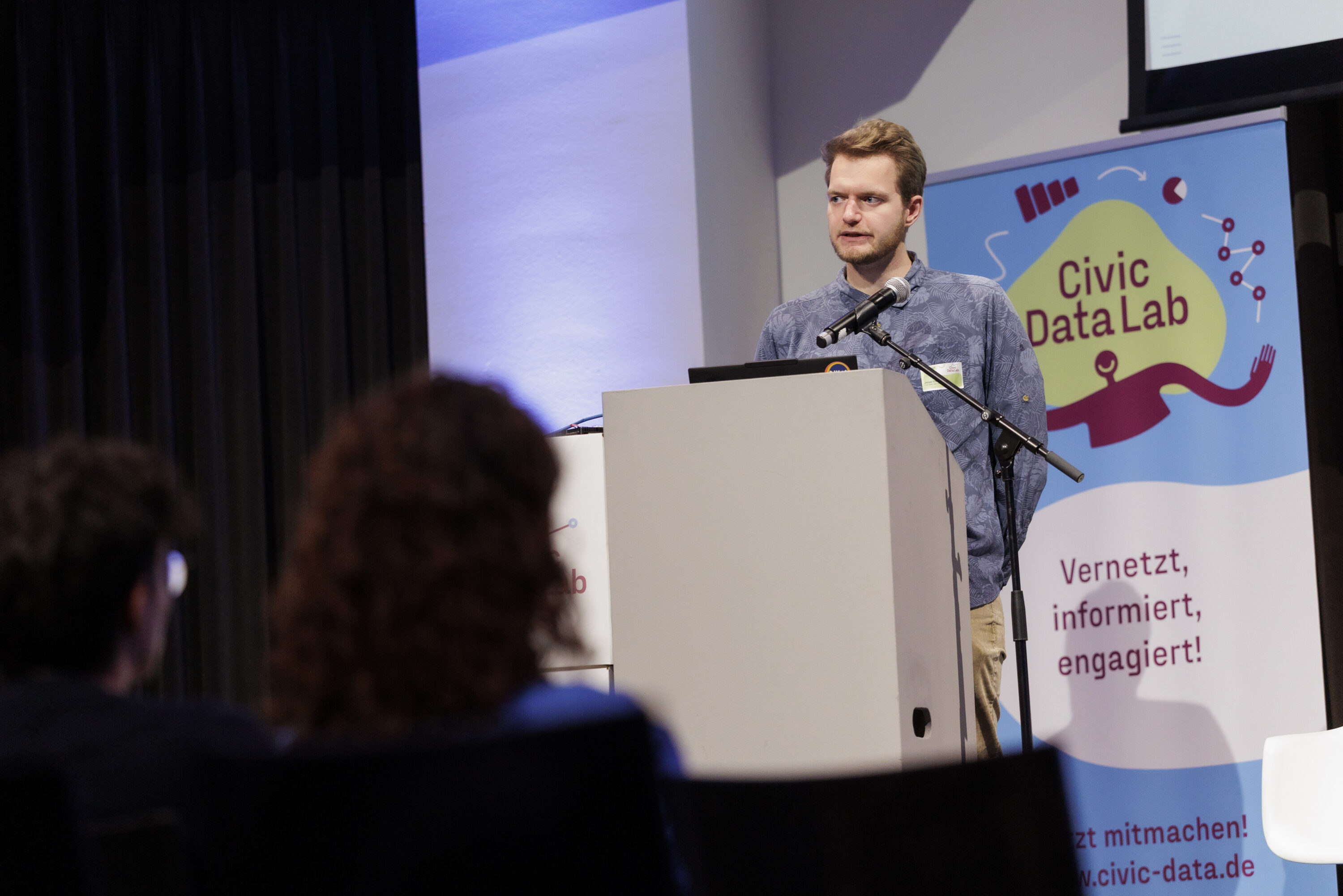 Man sieht Jonas Stettner, der auf der Bühne einen Vortrag zum Thema Self Hosted LLMs präsentiert.